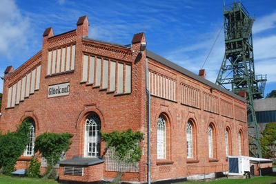 Ein Backsteingebäude mit einem Förderturm im Hintergrund