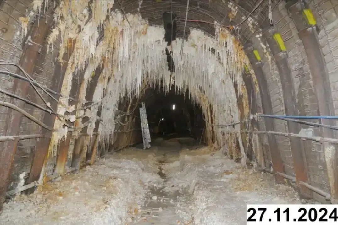 Foto einer bogenförmigen Strecke unter Tage. An den Seiten und der Decke bilden sich weiße Verkrustungen.