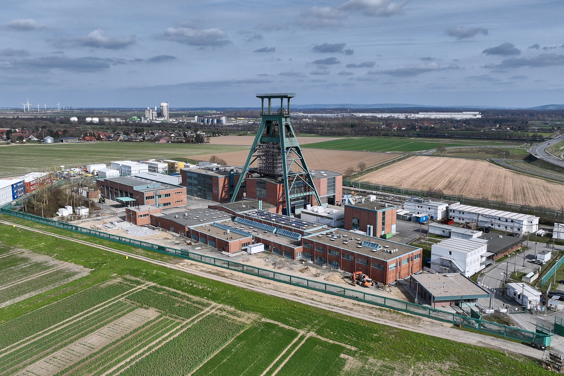 Luftaufnahme der Schachtanlage Konrad 1 mit dem denkmalgeschützten Fördergerüst. Ringsum erstrecken sich Felder.