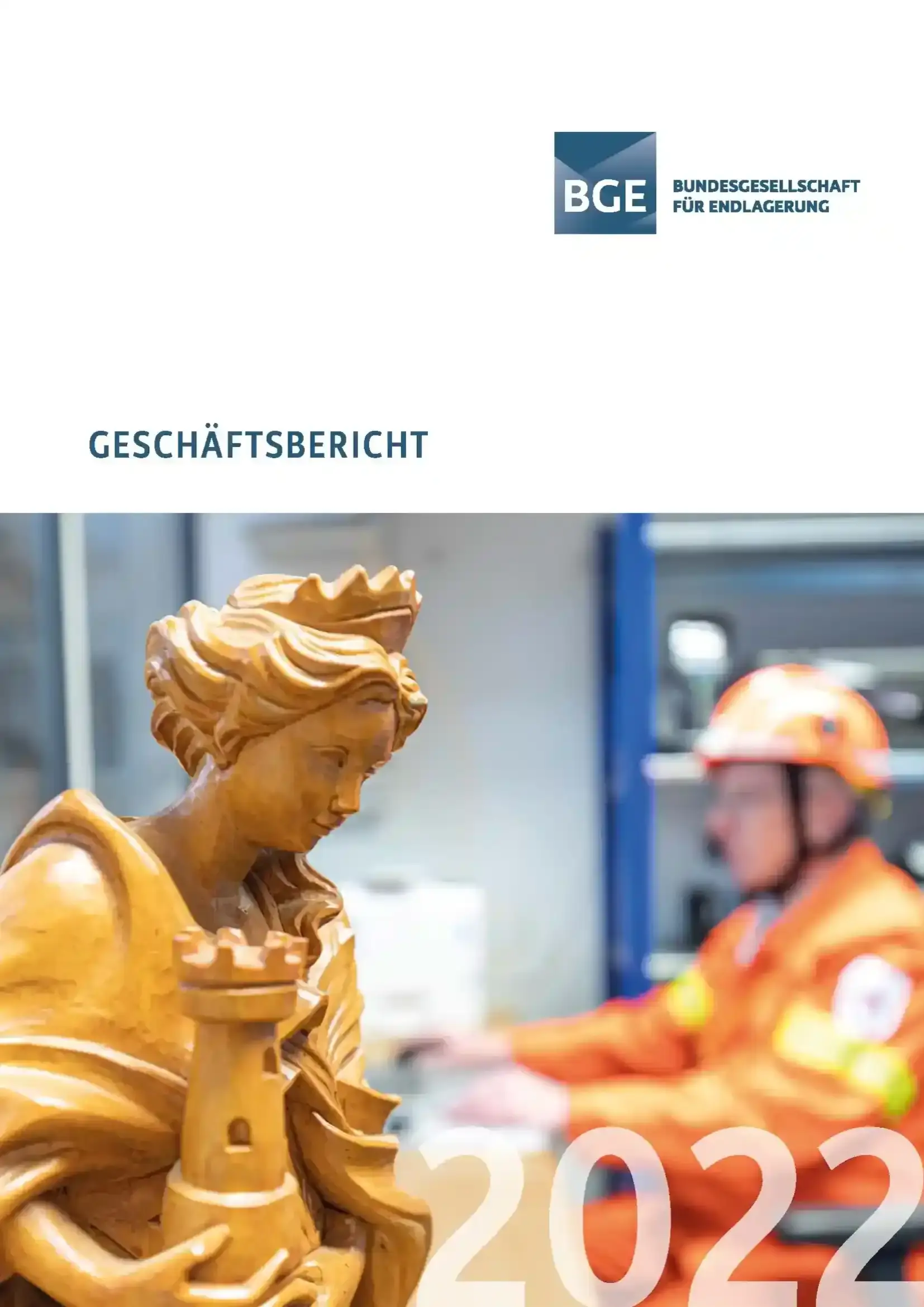 Das Cover des Geschäftsberichts 2022 zeigt eine geschnitzte Holzfigur im Vordergrund und einen Mann in orangefarbener Arbeitskleidung im Hintergrund. 