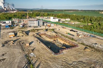 Baugrube in grüner Landschaft, Kraftwerk im Hintergrund