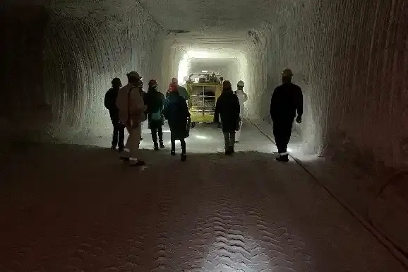 Sieben Personen laufen durch eine Strecke in einem Bergwerk.