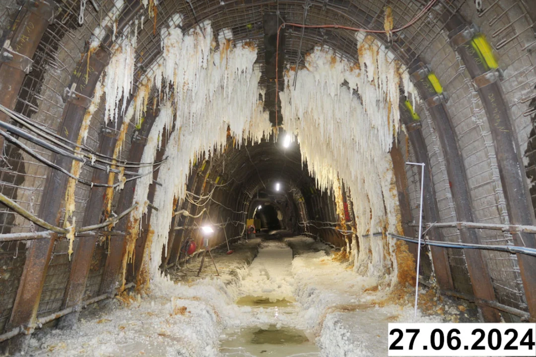 Foto einer bogenförmigen Strecke unter Tage. An den Seiten und der Decke bilden sich weiße Verkrustungen.