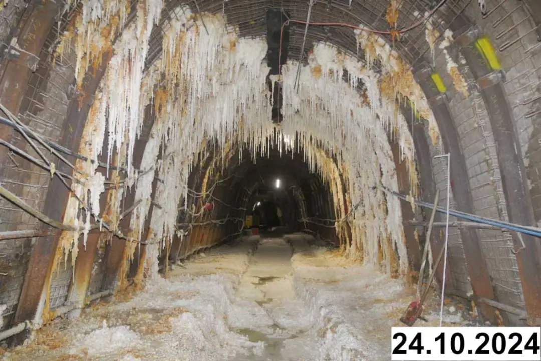 Foto einer bogenförmigen Strecke unter Tage. An den Seiten und der Decke bilden sich weiße Verkrustungen.