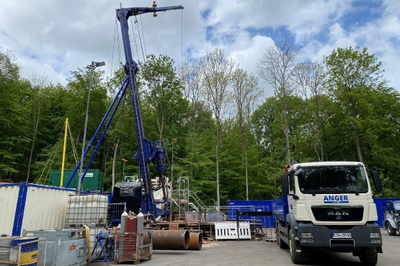 Auf dem Bild ist der Bohrplatz im Wald zu sehen. Auf der Baustelle ist das Bohrgerät aufgestellt. Ein LKW steht daneben.