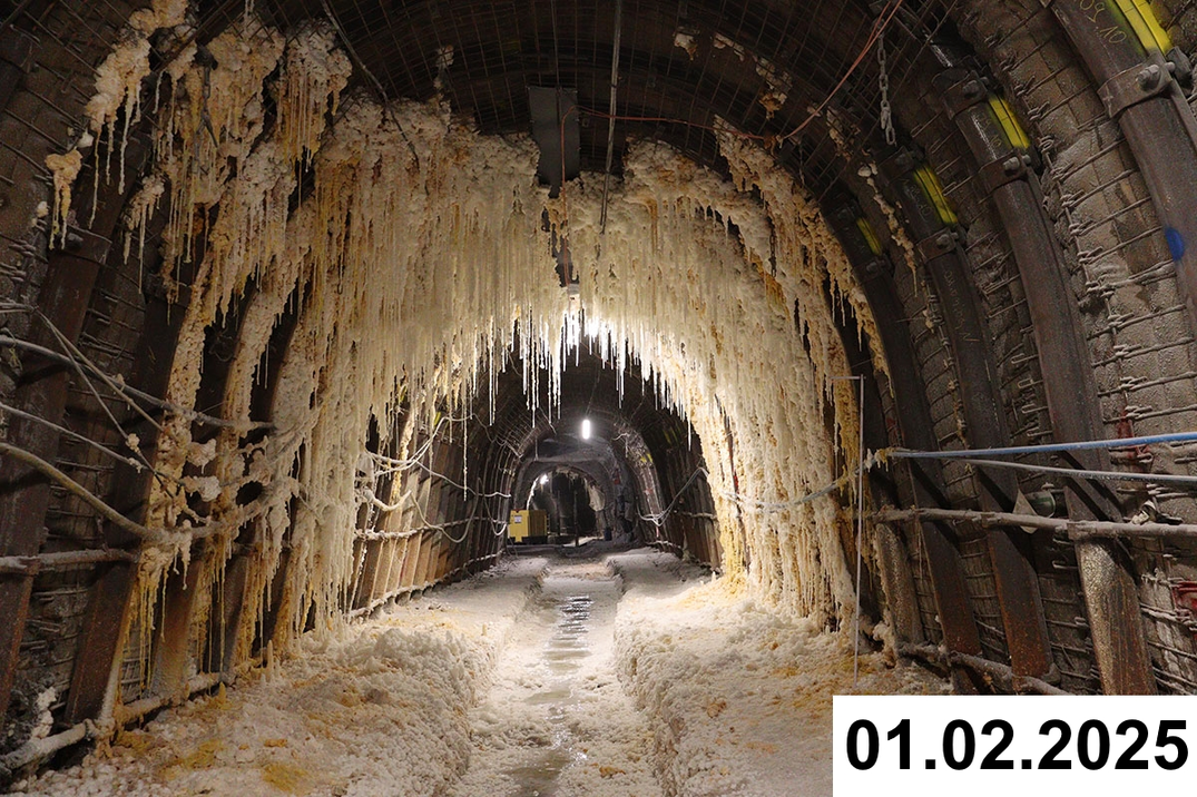 Foto einer bogenförmigen Strecke unter Tage. An den Seiten und der Decke bilden sich weiße Verkrustungen.