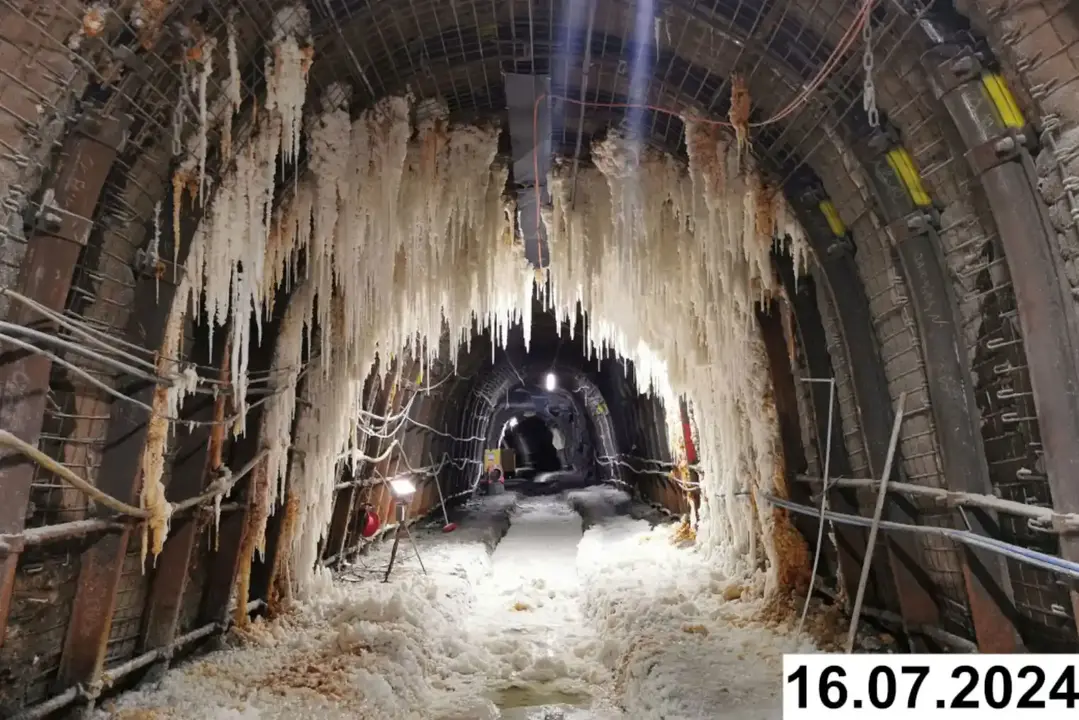 Foto einer bogenförmigen Strecke unter Tage. An den Seiten und der Decke bilden sich weiße Verkrustungen.