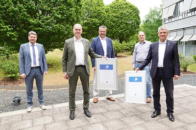 5 Personen stehen draußen, 2 von ihnen halten je ein Zertifikat in der Hand