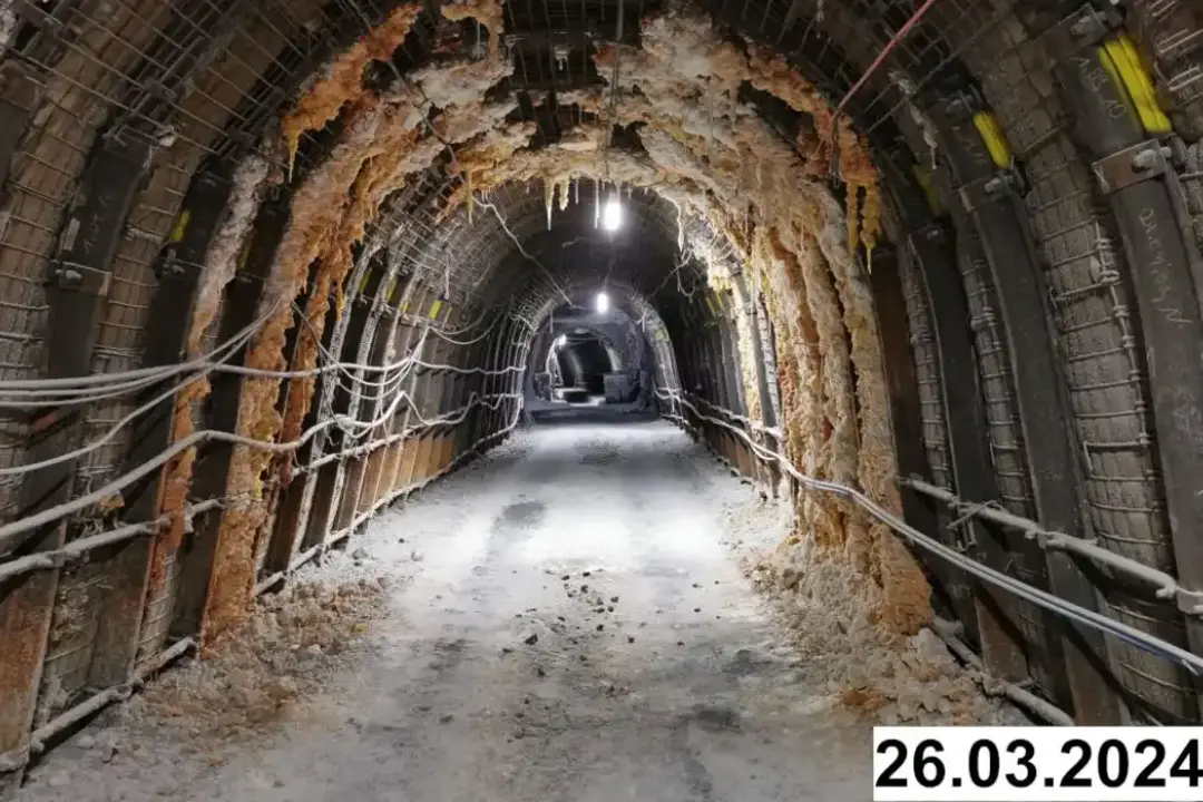 Foto einer bogenförmigen Strecke unter Tage. An den Seiten und der Decke bilden sich weiße Verkrustungen.