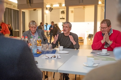 Mehrere Personen sitzen um einen Tisch und sind miteinander im Gespräch.