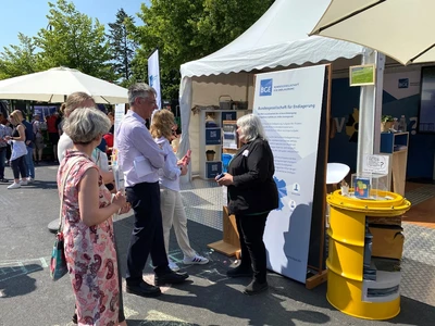 Zu sehen ist der Messestand der BGE mit mehreren Besuchern, welche sich im Dialog befinden, oder die Infoaufsteller lesen.