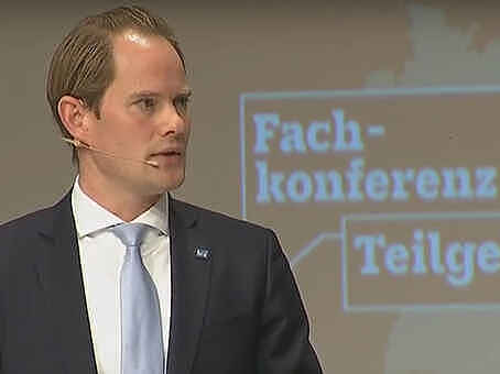 Ein Mann im Anzug vor dem Logo der Fachkonferenz Teilgebiete