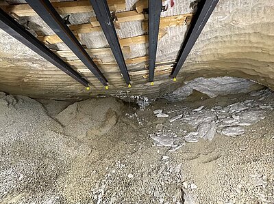 Der Blick geht in einen Hohlraum unter Tage. Schotter ist zu sehen, der bis unter die Decke der Kammer reicht. Salzbrocken haben sich zum Teil von der Decke gelöst und sind herabgefallen.