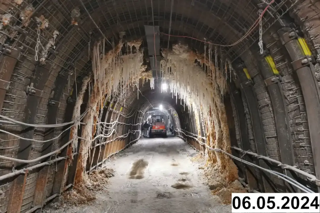 Foto einer bogenförmigen Strecke unter Tage. An den Seiten und der Decke bilden sich weiße Verkrustungen.