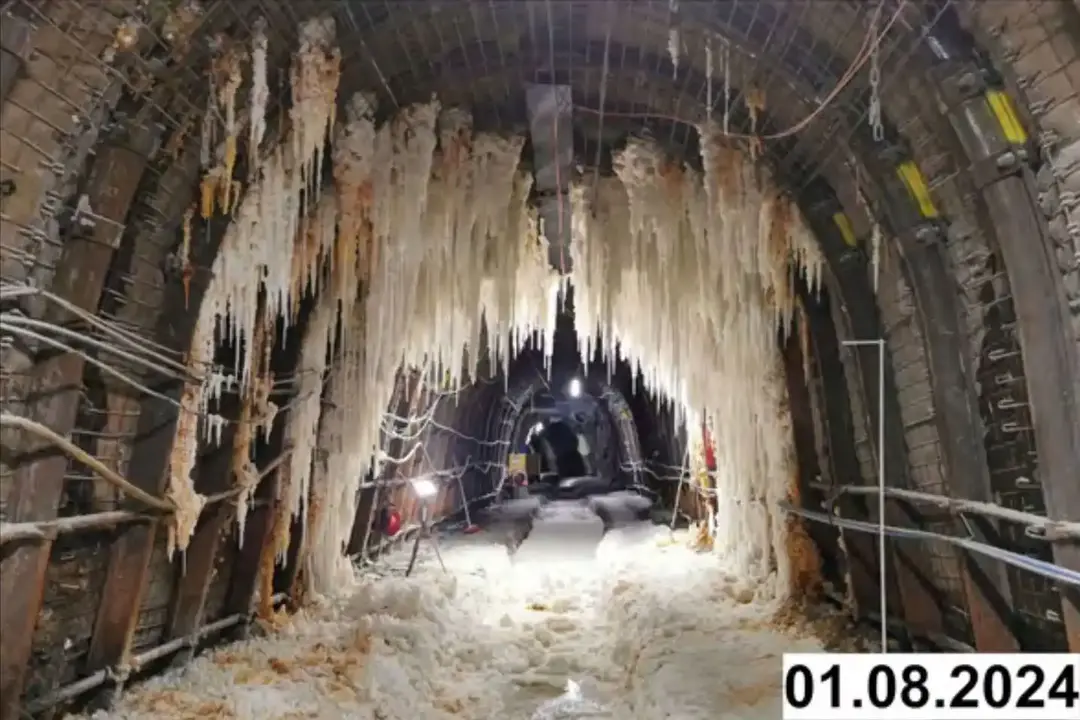 Foto einer bogenförmigen Strecke unter Tage. An den Seiten und der Decke bilden sich weiße Verkrustungen.